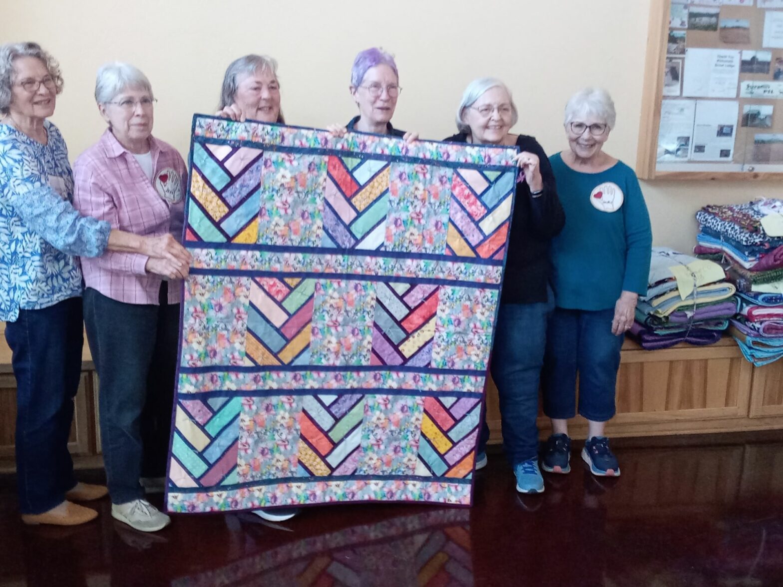 Members of Quilts from Caring Hands holding up a quilt.