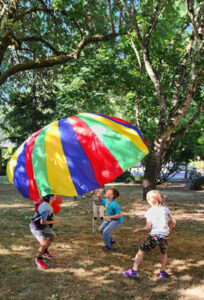 Children playing under rainbow colored parachute